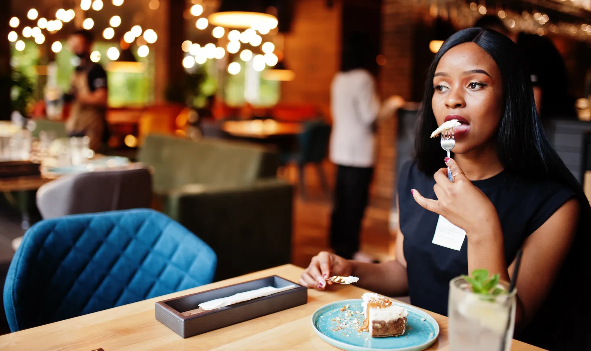 Une cliente déguste un dessert dans un restaurant, souriante.