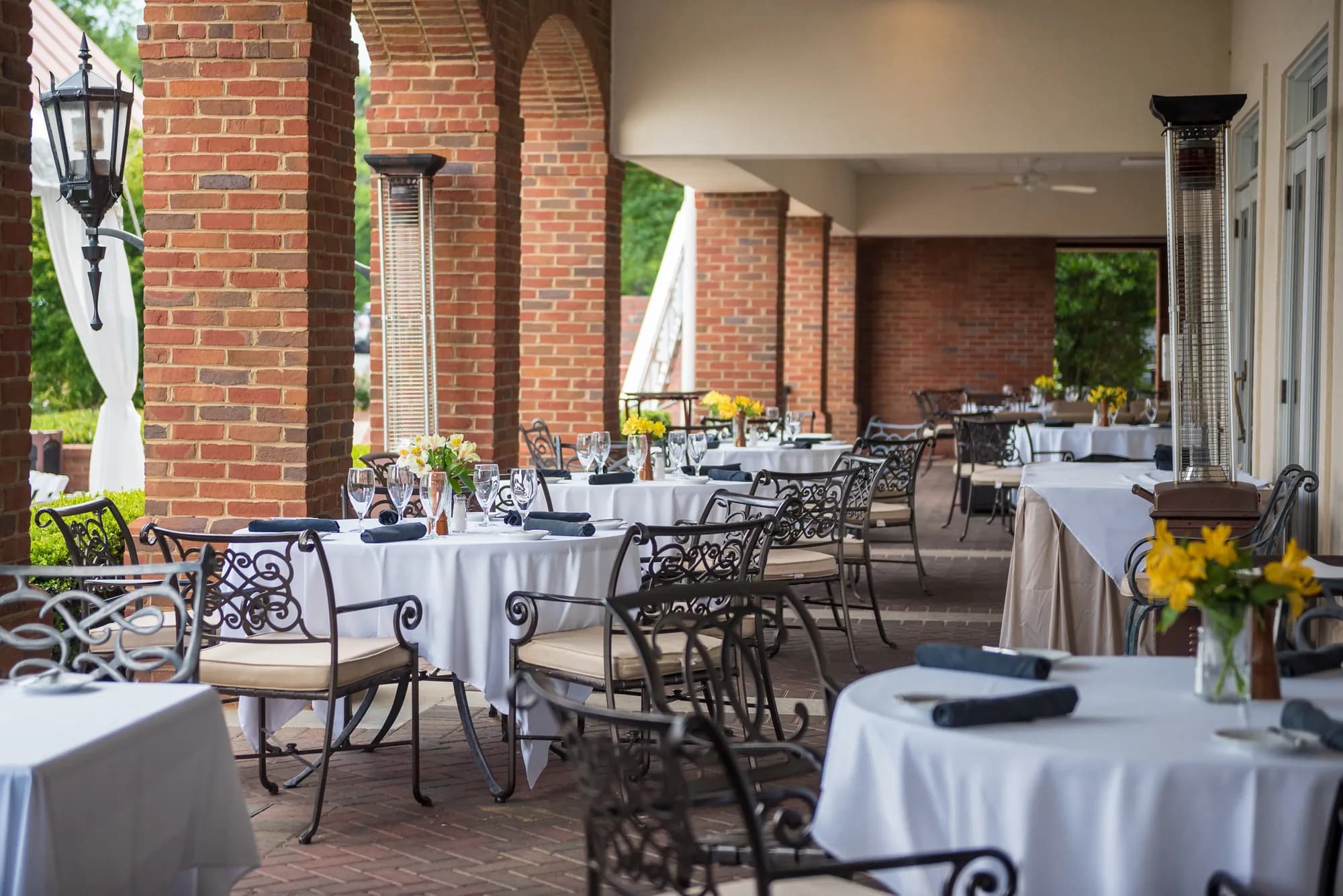 Terrasse de restaurant dressée pour un événement, tables alignées en extérieur.